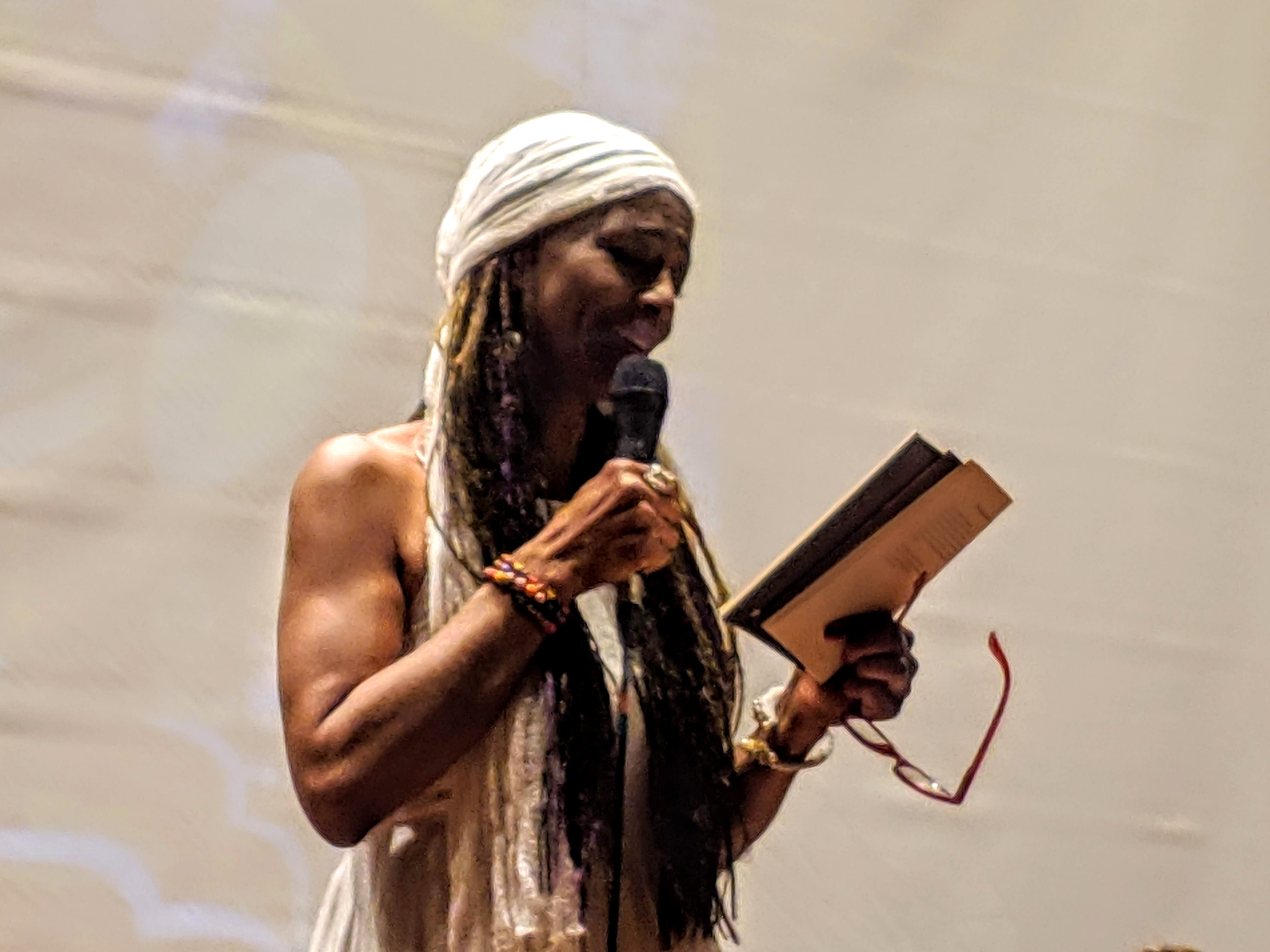 Ilustración del interior del libro: una mujer con trenzas, turbante blanco, micrófono y libro abierto